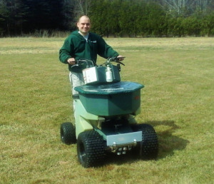 Valley Green Companies employee riding green lawn overseeding machine.