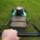 Man’s hand on push lawnmower.