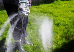 A woman spreads fertilizer on her lawn.