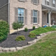 A mulch bed with ornamental plants surrounding a house.